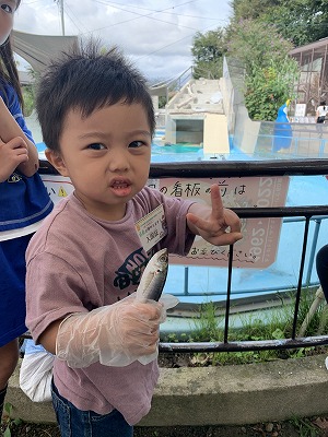 魚を持ってこちらを向いている男の子の写真