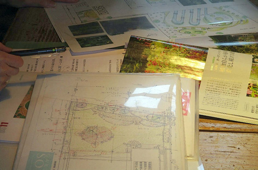 お庭の設計図や参考になる雑誌、写真などを見ながら庭の設計をする写真