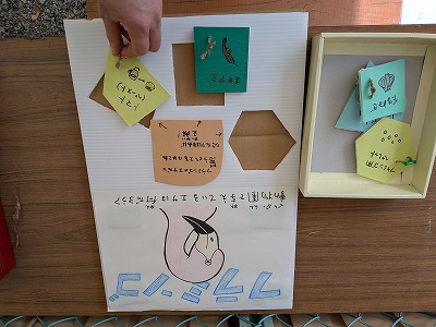 フラミンゴのイラストの下に切り抜いた窪みと切り抜かれた型。型には動物のエサの名称とそのイラストが書かれている